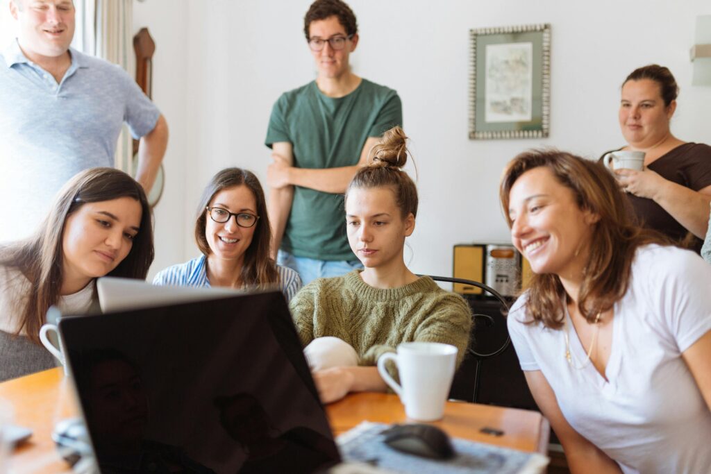 pexels-photo-1595391-1595391 A diverse group of adults at work, enjoying a casual meeting indoors with focus and smiles.